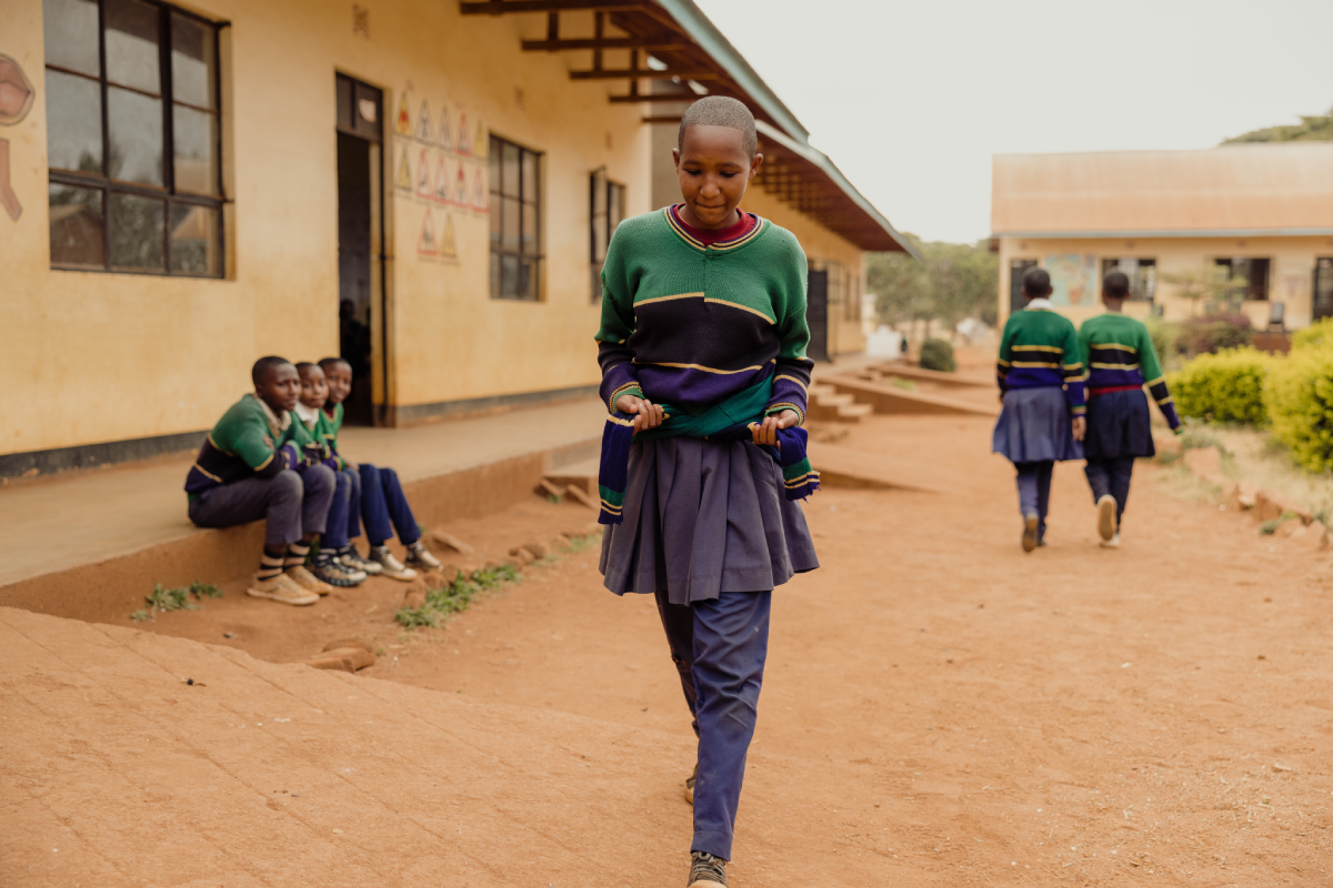 A girl wraps an extra sweater around her waist to hide period stains on her school uniform.