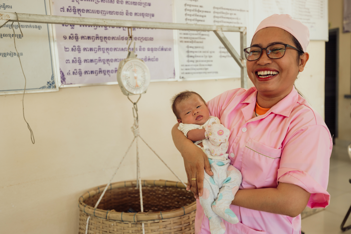Vannak joyfully smiles, holding an infant in her arms.