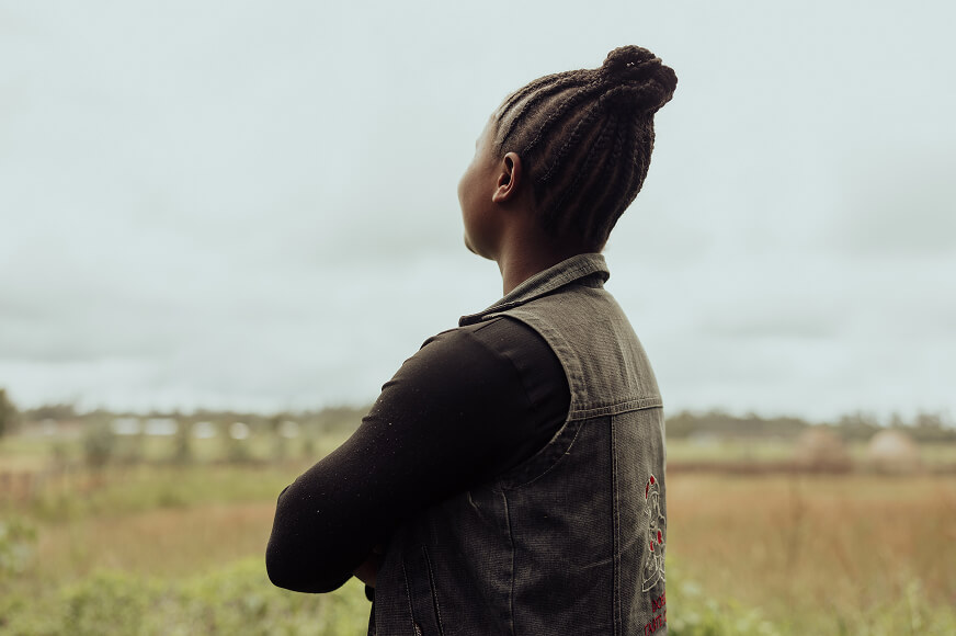Alt-text: A woman confidently looks off into the distance with her arms crossed.